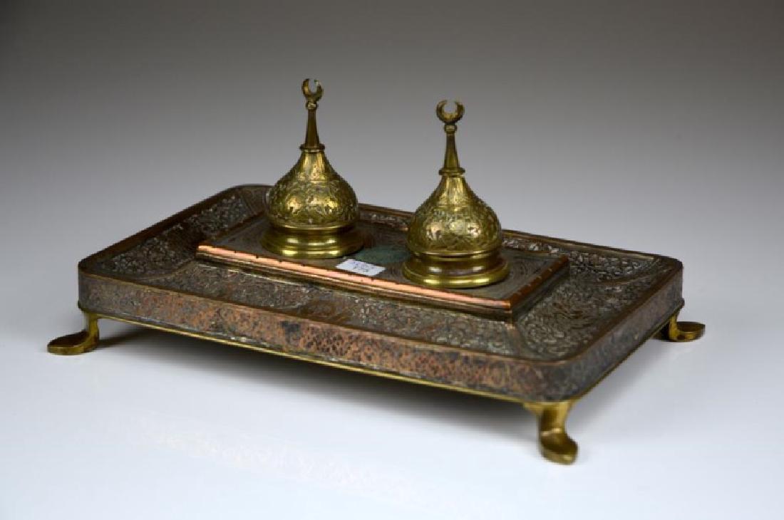 PERSIAN ANTIQUE COPPER INKSTAND: Rectangular form raised on four feet. Each inkpot with a domed lid and crescent finial, 19th C. L 25.4 cm. (10 in.)
