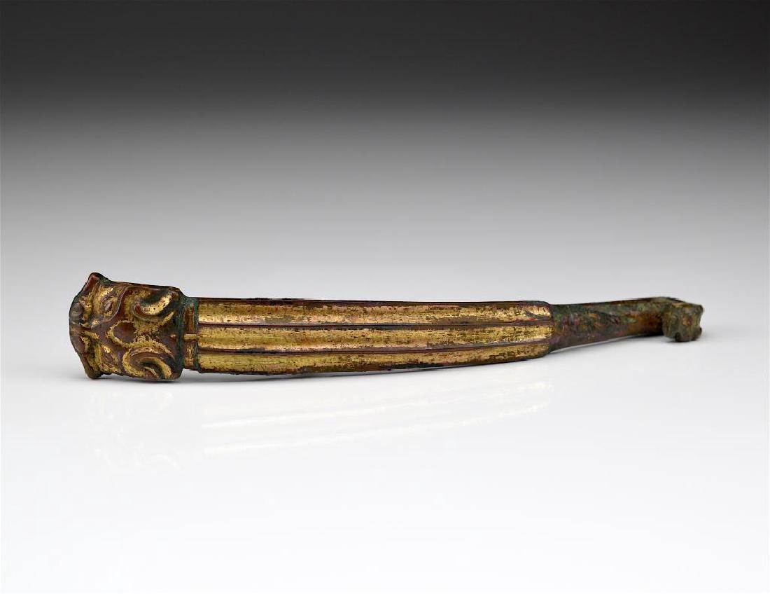 CHINESE ARCHAIC BRONZE TAOTIE BELT HOOK: With gilding and red patina to body. Han dynasty. L. 18cm (7 1/8 in).