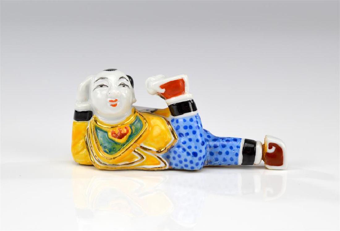 Chinese famille rose figural snuff bottle: Of a reclining boy. L. 7.5cm (3 1/8 in.)