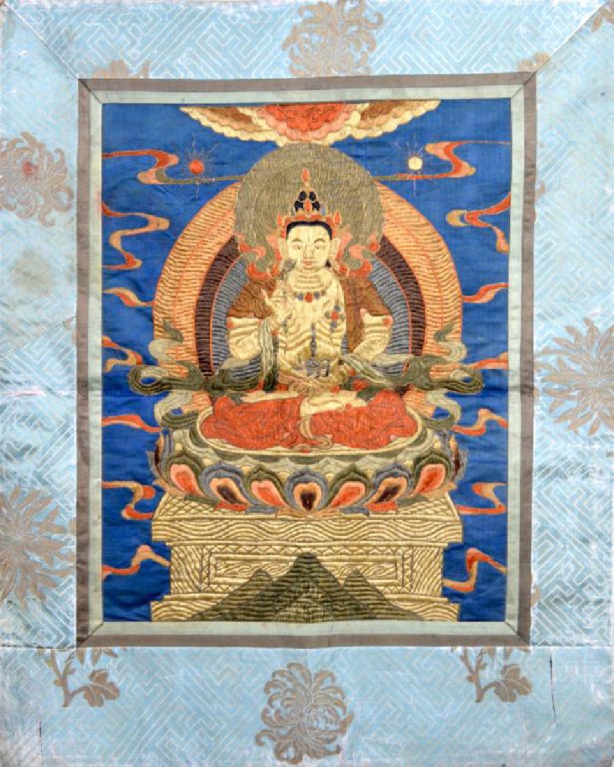 CHINESE SILK EMBROIDERED BUDDHIST THANGKA: Of Avalokiteshvara sitting on a lotus throne against deep blue background. Border with stylized swastika and floral. With gold threaded outlines, Qing dynasty. Size: 68 x 54cm (26 3/4 x 21 1/4 in.)