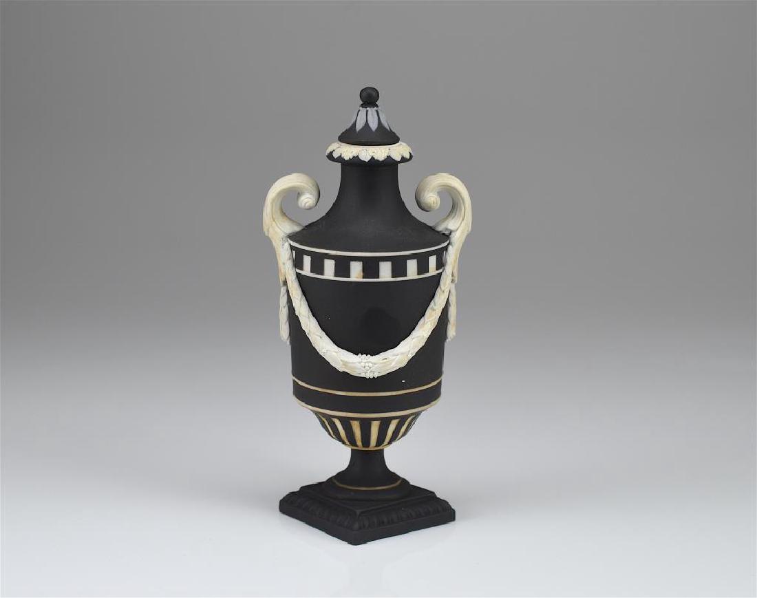 Wedgwood black basalt Jasperware covered vase: On a square base, with garland swags and engine turning decoration. Incised Wedgwood to base. 18th C / 19th C. H 17.8 cm (7 in.)