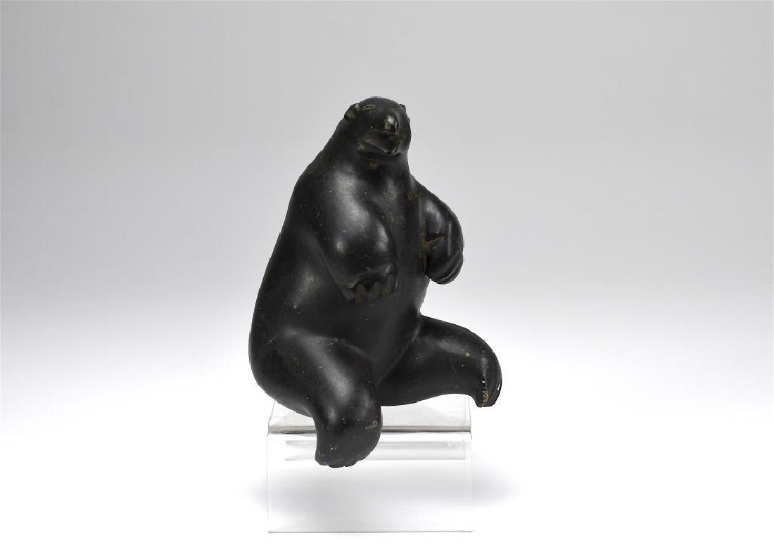 JOHNNY KASUDLUAK (1935 - ): Seated bear.Black soapstone Inuit carving.Disc number E91669 to base.Kuujjuaraapik , Great Whale River. H 6 1/2 in. (16.5 cm) Minor surface scratches to body. Minor chips to one foot.