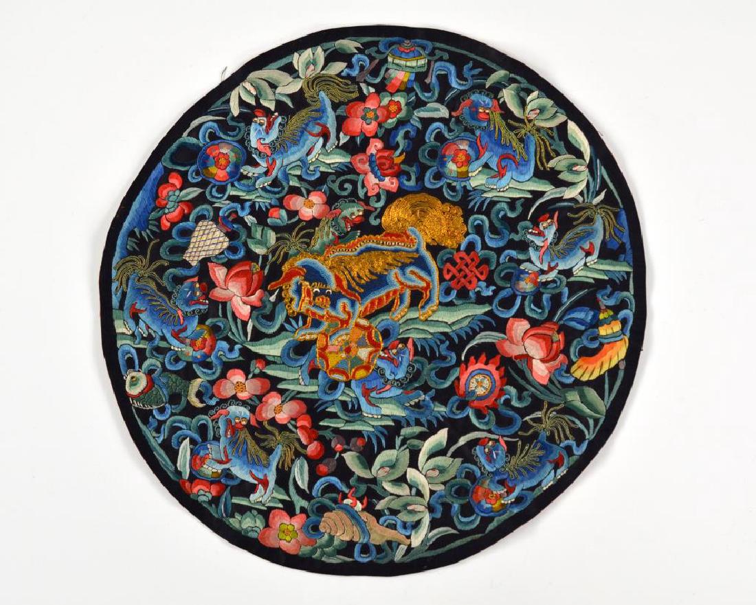 CHINESE BLUE GROUND SILK EMBROIDERED ROUNDEL: Embroidered with silk and gold threads, of seven lions playing with floral balls, together with eight Buddhist emblems and florals. Old sticker label to back. Dia. 33cm (13 in.)