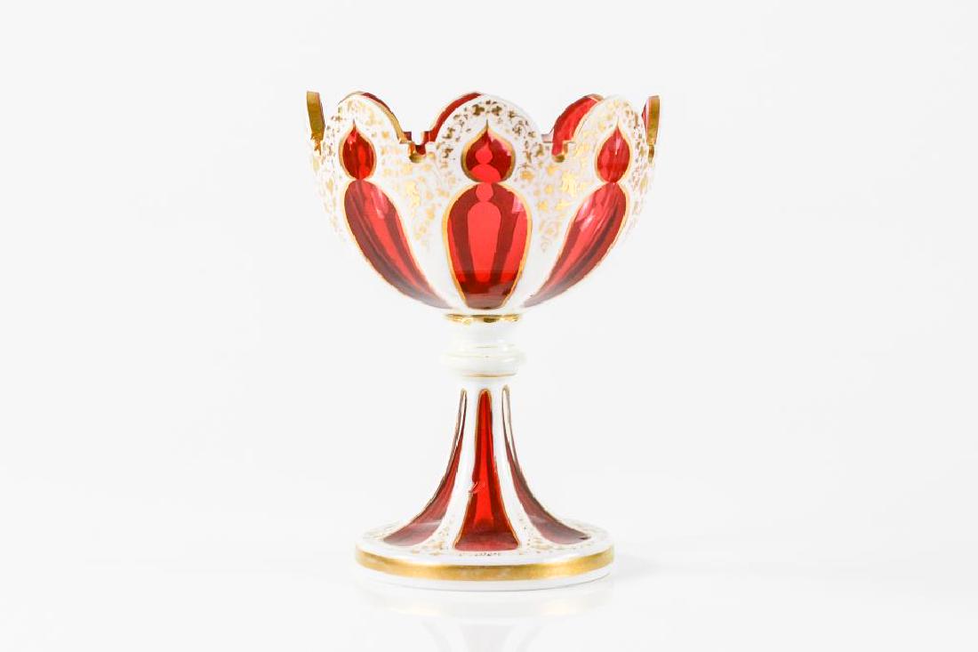 Bohemian cased cranberry glass pedestal bowl: Cranberry glass with cased white exterior and gilt foliate decoration. H. 18.4 cm (7 1/4 in.)