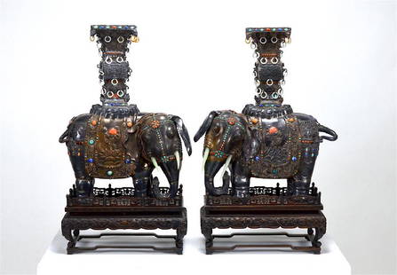 PAIR OF CHINESE SILVER ELEPHANTS WITH JEWELS: The elephants with a Gu form vase to top, body with mountain and clouds and Eight Buddhist Emblems theme motifs. Inset with turquoise, corals, and lapis lazuli cabochons, and jade tusks. With wood