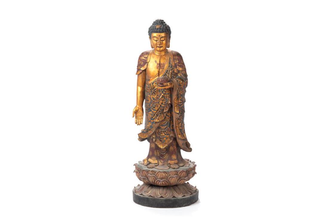 LARGE CHINESE POLYCHROME & GOLD WOOD BUDDHA: Standing on a double lotus throne with the right hand pointed downward, and left hand holding a lotus bowl. H. 110cm (43 1/4 in.)
