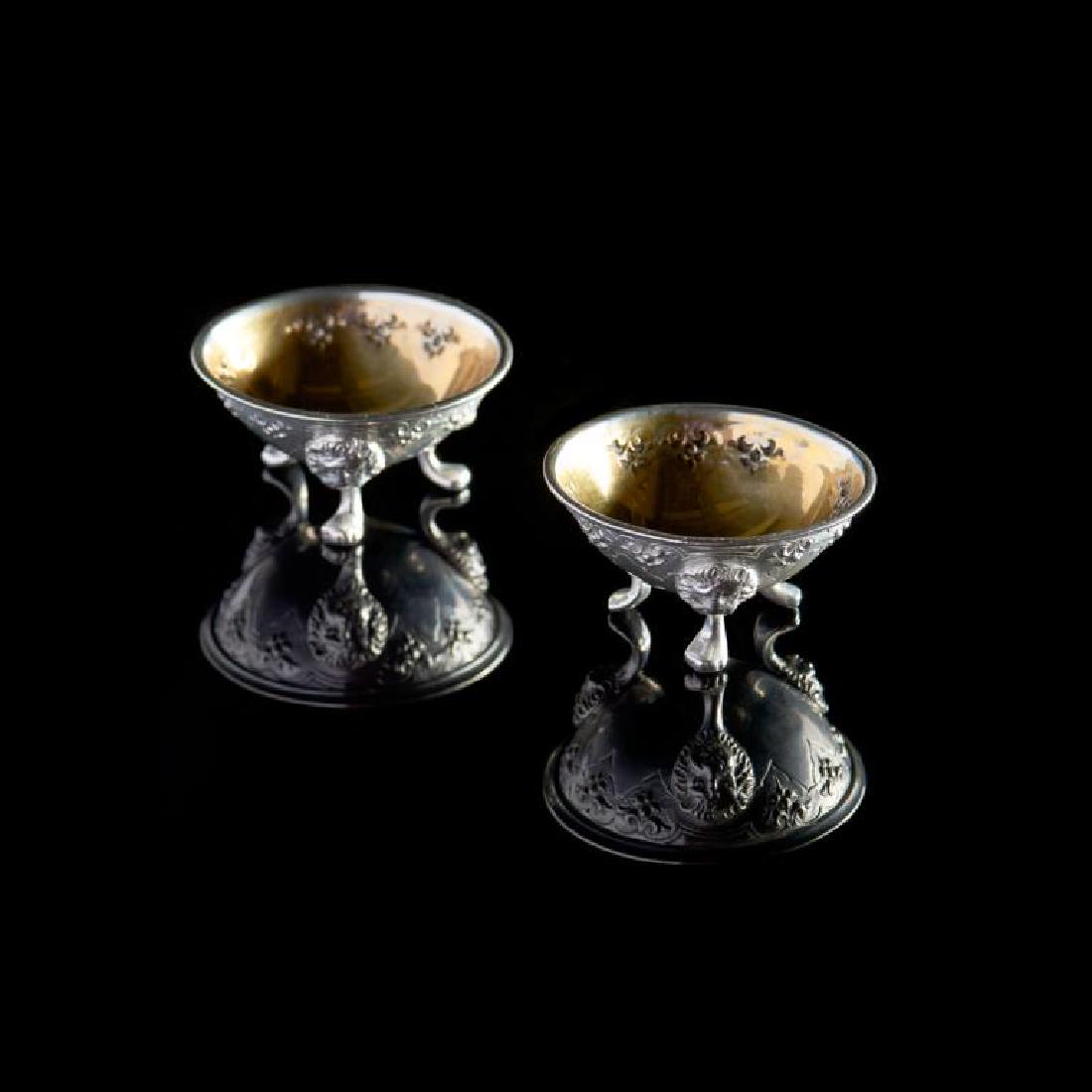 Pair of Victorian English silver salts: Each 19th C salt cellar raised on three lion capped feet, with repousse decorative band and silver gilt interior. London, 1869. George Fricker. 59g. Dia. 5.4 cm (2 1/8 in.)