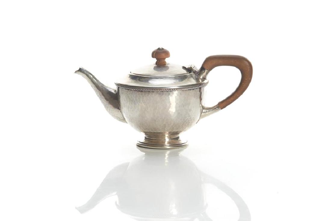 English Arts & Crafts silver teapot: Hammered body with turned wood handle and finial. Marked 838. Birmingham, 1922. Albert Edward Jones (A.E. Jones). 222g. t.w. L. 19.7 cm (7 3/4 in.)