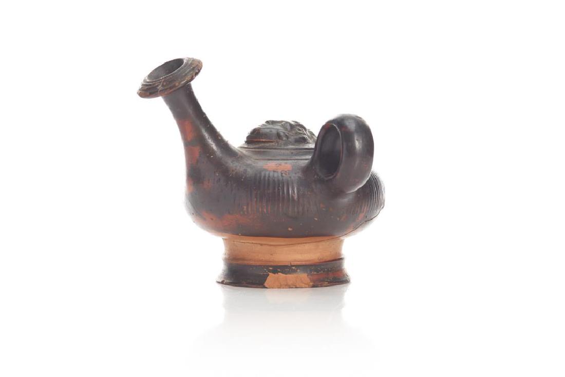 Greek terracotta pottery oil lamp filler: Black glaze finely reeded body, mask detail to top. Restored and chips to base. H 12cm (4 3/4in)