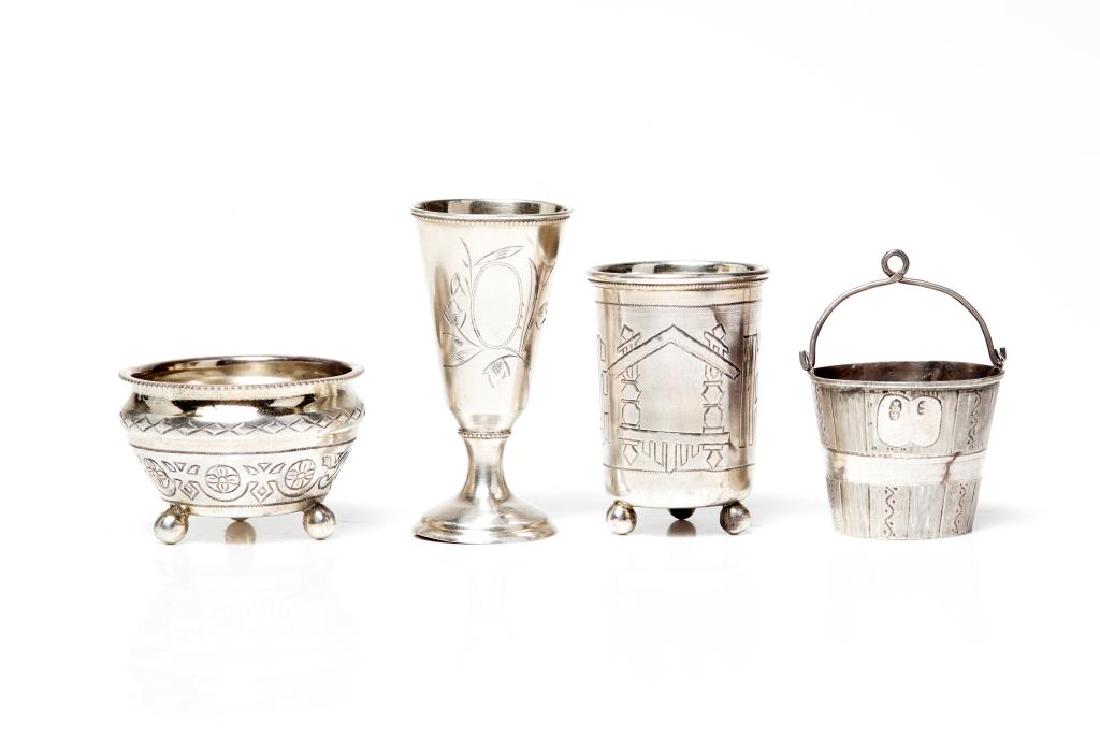 Four pieces of Russian silver: Two vodka cups, one footed. Together with a salt cellar and tea strainer. Two pieces marked for Moscow, one 19th C piece marked 1893. Tea strainer marked for Kostroma. All marked 84. 92g.
