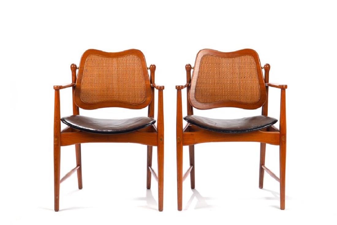 Eight teak mid century modern dining chairs: designed by Arne Vodder, circa 1956, made by France & Daverkosen (later France & Sons). With rattan swing backs and black leather seats, 2 arm chairs and 6 side chairs, h. 32 in. w 21 1/4 in.