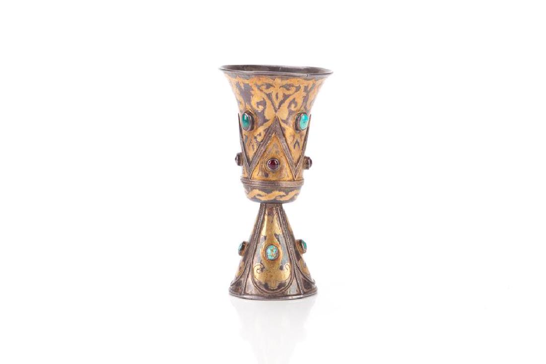 GILT SILVER CENTRAL ASIAN ISLAMIC CUP WITH GEMS: Exterior struck with floral patterns and beaded borders. Inset with turquoise and rubies cabochons. 18th C. H. 13cm (5 in.) Weight: 86g.