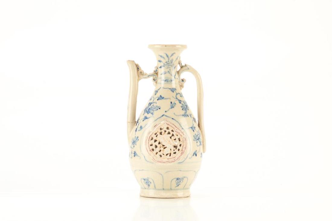 HOI AN HOARD BLUE & WHITE PORCELAIN EWER: The pear-shaped ewer painted in the Chinese Ming dynasty style to the exterior with flower and leafy scrolls. Strap handle and a spout connected by bridge. Main body with a double wall openworkcartouc