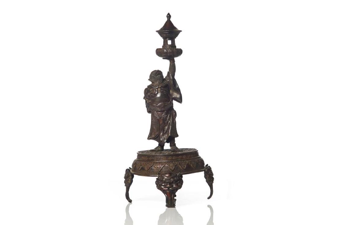 JAPANESE BRONZE MONKEY FORM OIL LAMP: Circular platform standing on four legs with mask heads. The body cast with a monkey holding a lantern form lamp top. Meiji period. Overall height: 38cm (15 in.)