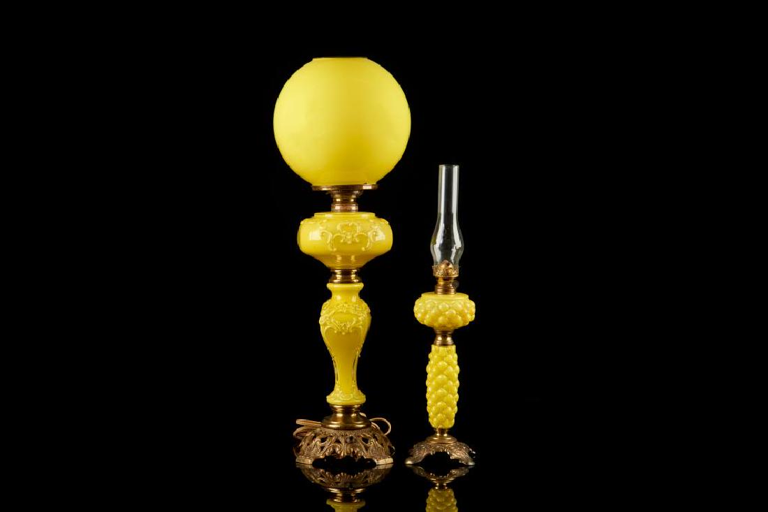Two American yellow cased glass parlor lamps: One parlour lamp is electrified with bulbous shade and raised scrolling acanthus leaf decoration. Together with a smaller oil lamp with tufted pattern. Both raised on pierced gilt metal bases.H. of ta