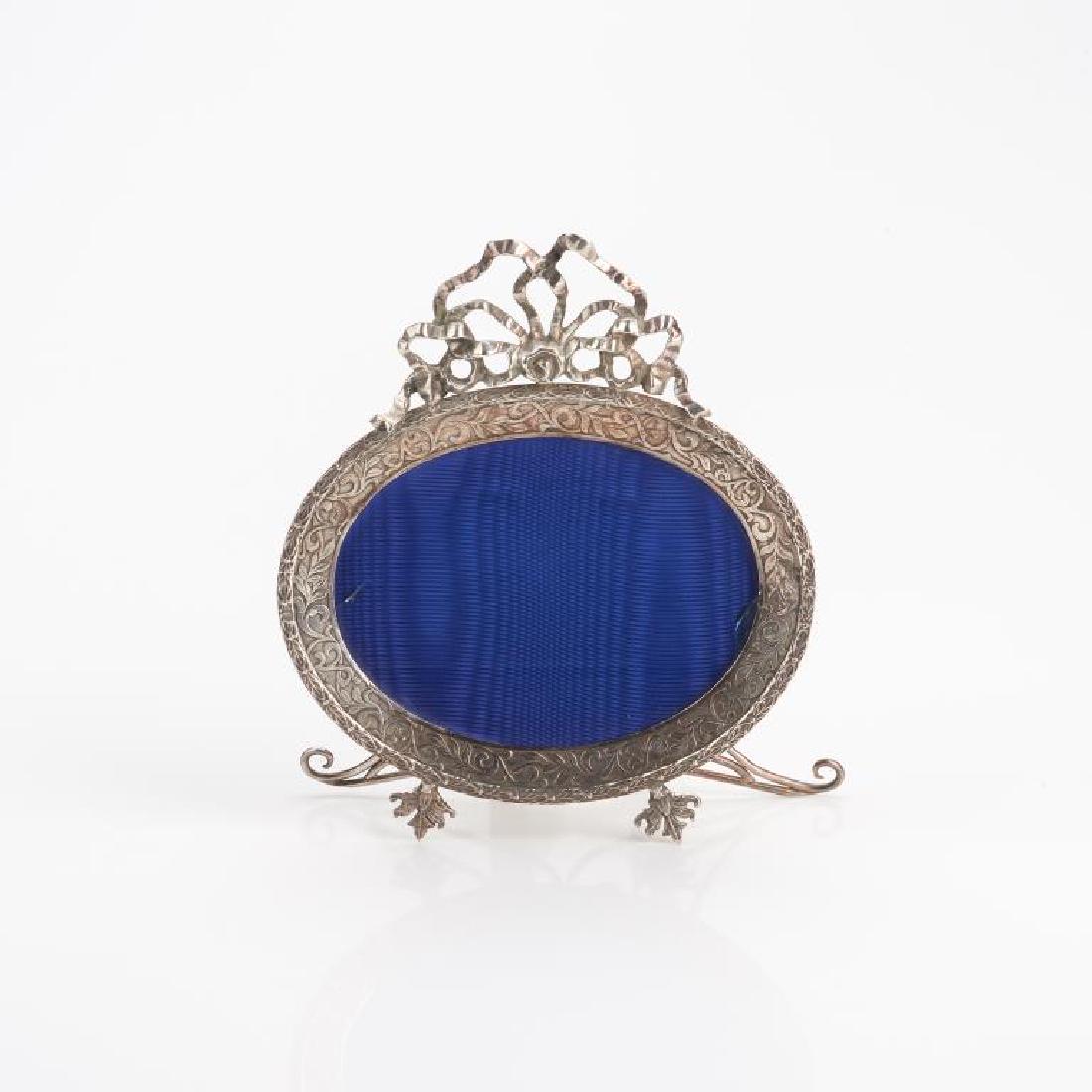 Russian oval silver picture: Foliate design, raised on matching feet, ribboned top, the back easel accented with a crown and natural back, with Russian hallmarks, Faberge makers mark for Oscar Pihl. L 4 7/8in. BIDDERS LIVING OUTS