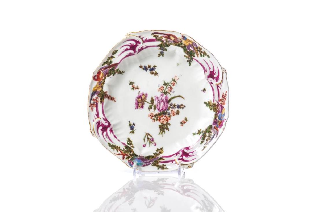 An early English hand painted porcelain plate: Puce border accented with birds, floral sprays in the centre, Chelsea with gold anchor mark, 1760-65. Dia 8 1/2in. Chip to rim, surface wear to glaze.