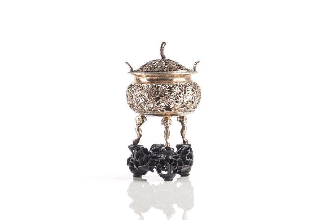 CHINESE EXPORT RETICULATED SILVER TRIPOD CENSER: Fine openwork bamboo decoration on a archaistic tripod ding form body. With fitted wood openwork stand. Base marked HC and Chinese. H. 10cm (4 in.) Overall weight with stand: 71g.