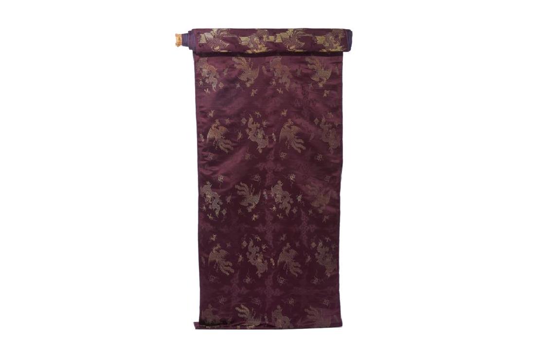 CHINESE SILK DRAGON & PHOENNIX TEXTILE ROLL: Purple ground silk woven with cloud patterns and gold embroidered dragon, phoenix, and flaming pearl patterns. End of roll with six character Zhang Xiang Fa factory label in gold.Approximately 22 mete