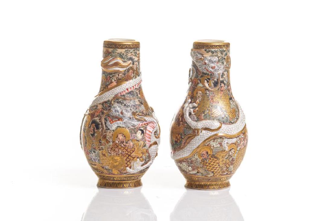 PAIR OF SATSUMA VASES WITH MOLDED DRAGONS: Each with a moulded white dragon to body, painted with various figures in landscape, signed Hozan to base. Meiji period. H. 19cm (7 1/2 in.)