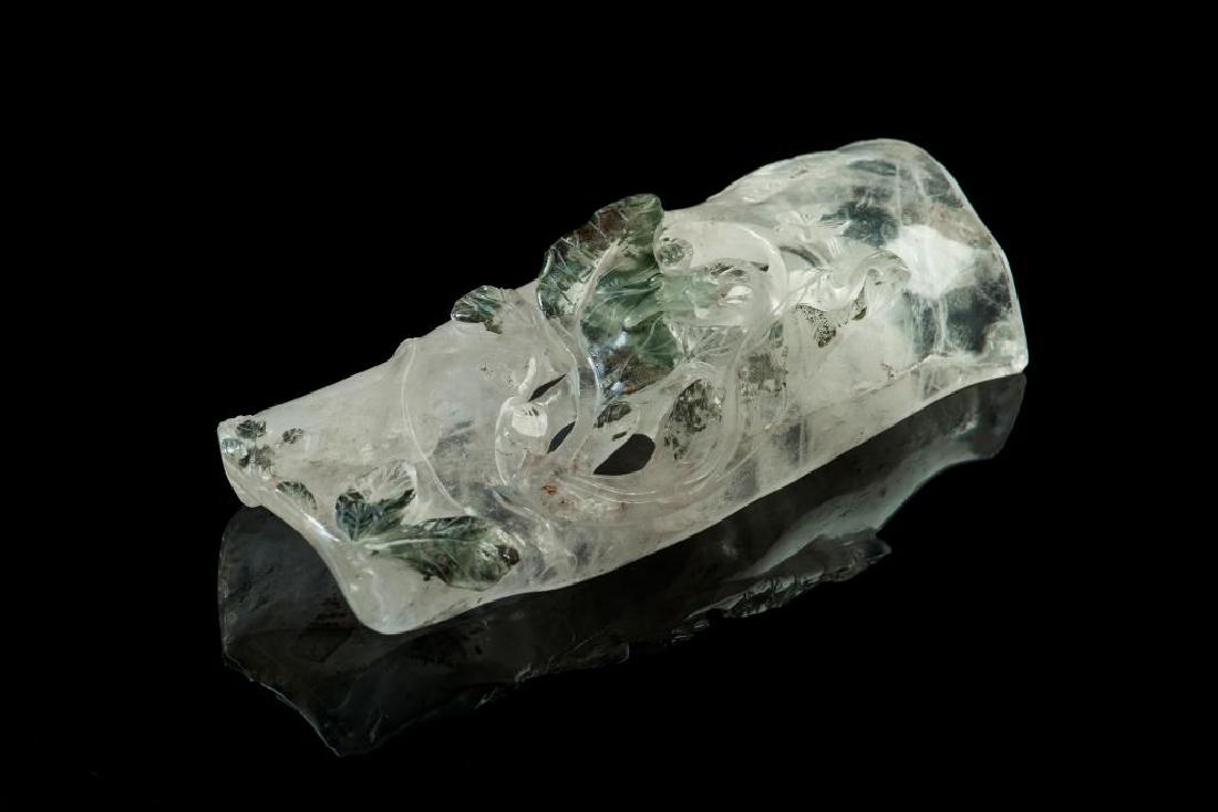 ROCK CRYSTAL CARVED SCHOLAR'S WRIST REST: Clear rock crystal with moss green inclusions. Carved as a bamboo shoot form armrest with relief and openwork decorations of leaves and insects. Shallow relief inscriptions carved to top left.L. 16cm 