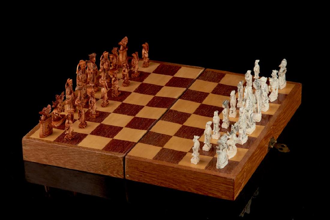 CHINESE NATURAL CARVED CHESS SET IN WOOD BOX: Including 16 pieces of white and 16 pieces stained. The pawns consist of Eight Immortals, and other pieces of figures, warriors, and castles. Tallest piece: 10cm (4 in.) Chess board size: 46 x 46cm (1