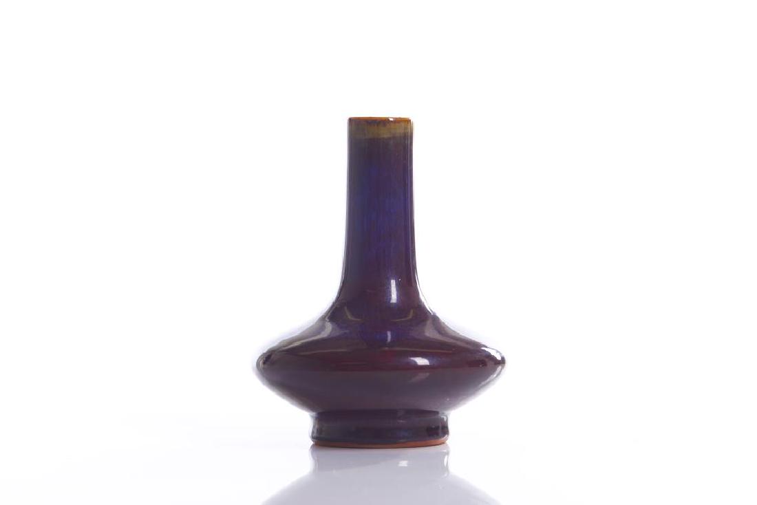 CHINESE FLAMBE GLAZED PORCELAIN BOTTLE VASE: The vase with a squat bulbous body with a long straight neck. Overall glazed in rich purple and blue flambe. Base with six character Qianlong mark, 19th C. H. 19cm (7 1/2 in.)
