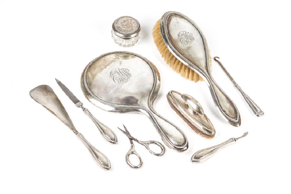 CANADIAN SILVER VANITY SET: Including hand mirror, brush, small dresser jar, and various nail implements. Monogrammed E M W. Total of nine pieces.