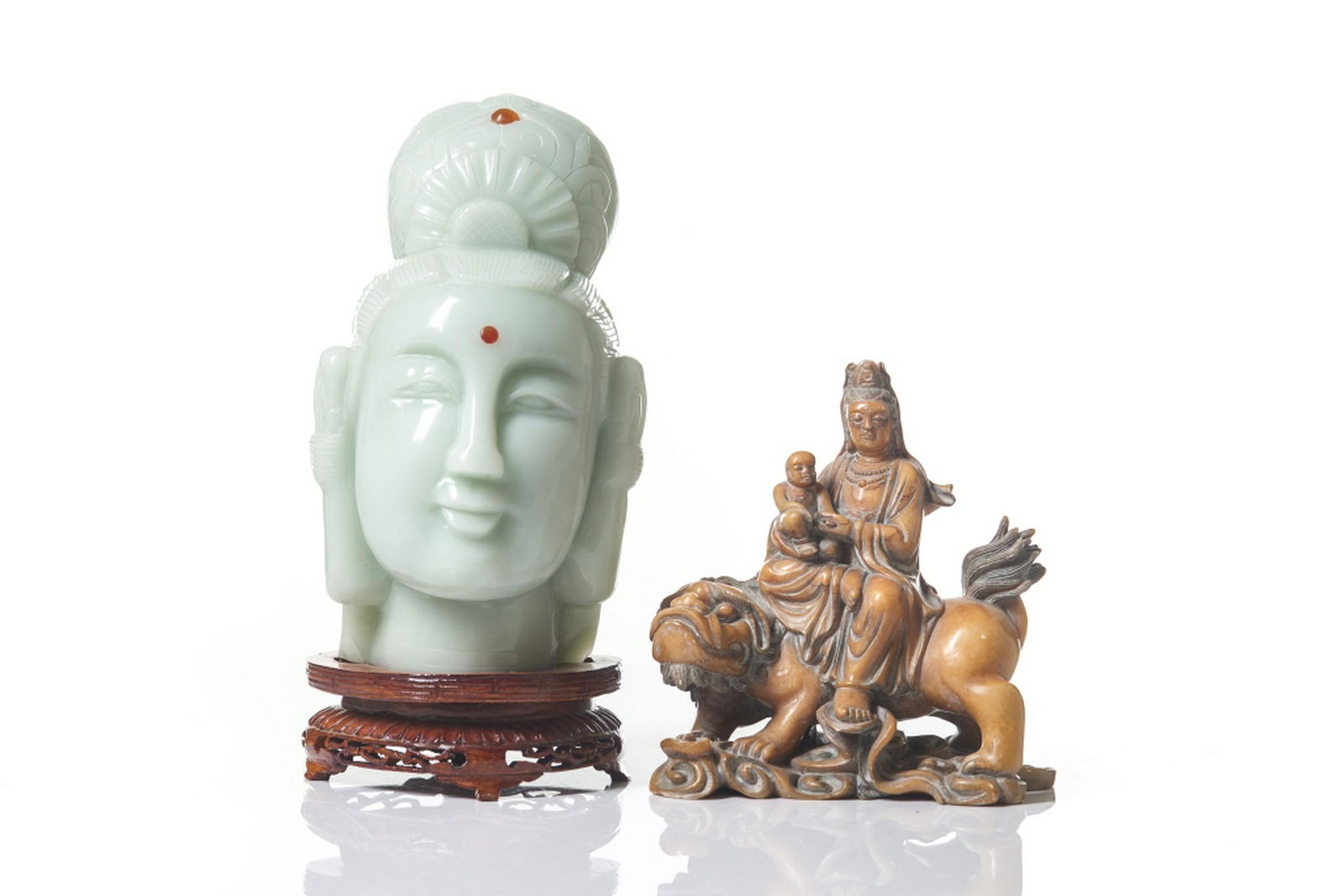 CHINESE JADE AND SOAPSTONE CARVED GUANYIN: One of a celadon Guanyin head on wood stand. The other of a bodhisattva with a child seated on a lion. Height of head on stand: 28cm (11 in.)