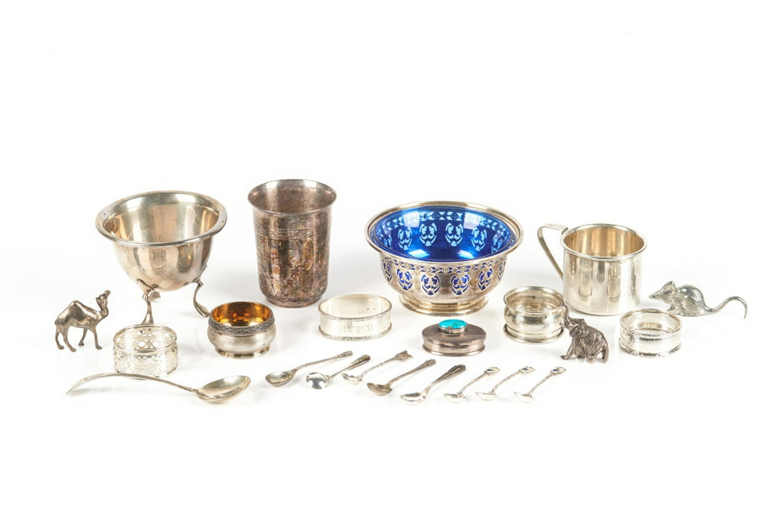 LOT OF SILVER TABLE ACCESSORIES: Comprising two mayonnaise bowls (one Birks with cobalt liner), one beaker, one mug, a salt cellar, six salt and two mustard spoons, four napkin rings, a snuff box, and three animals. 629g weighable si
