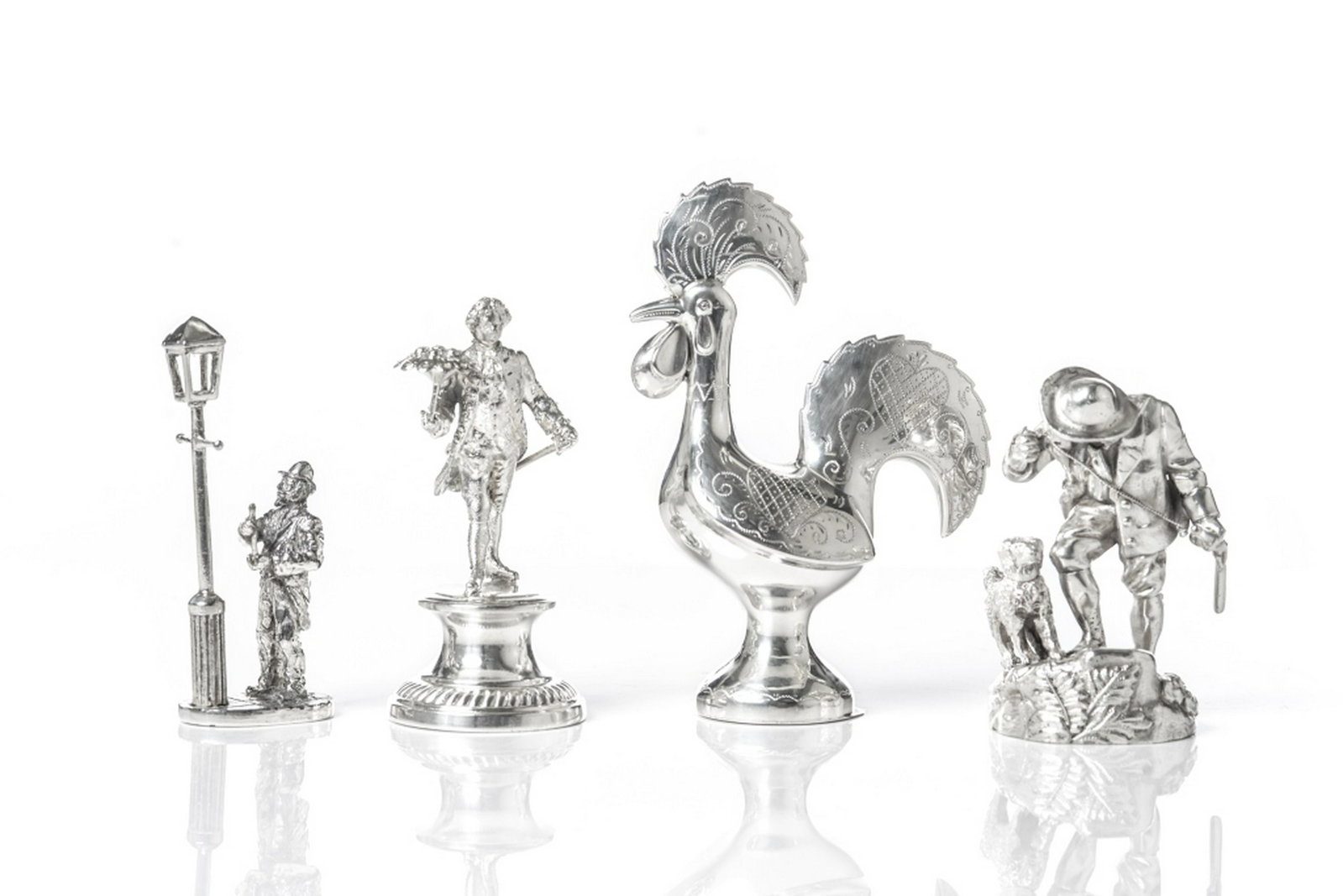 GROUP OF SILVER & SILVERPLATED FIGURES: Including a silverplated figure of a man on a pedestal with a bouquet of flowers, a silverplated figure of man with his dog, a silverplated man lighting a lamp, and a Continental sterling silver chick