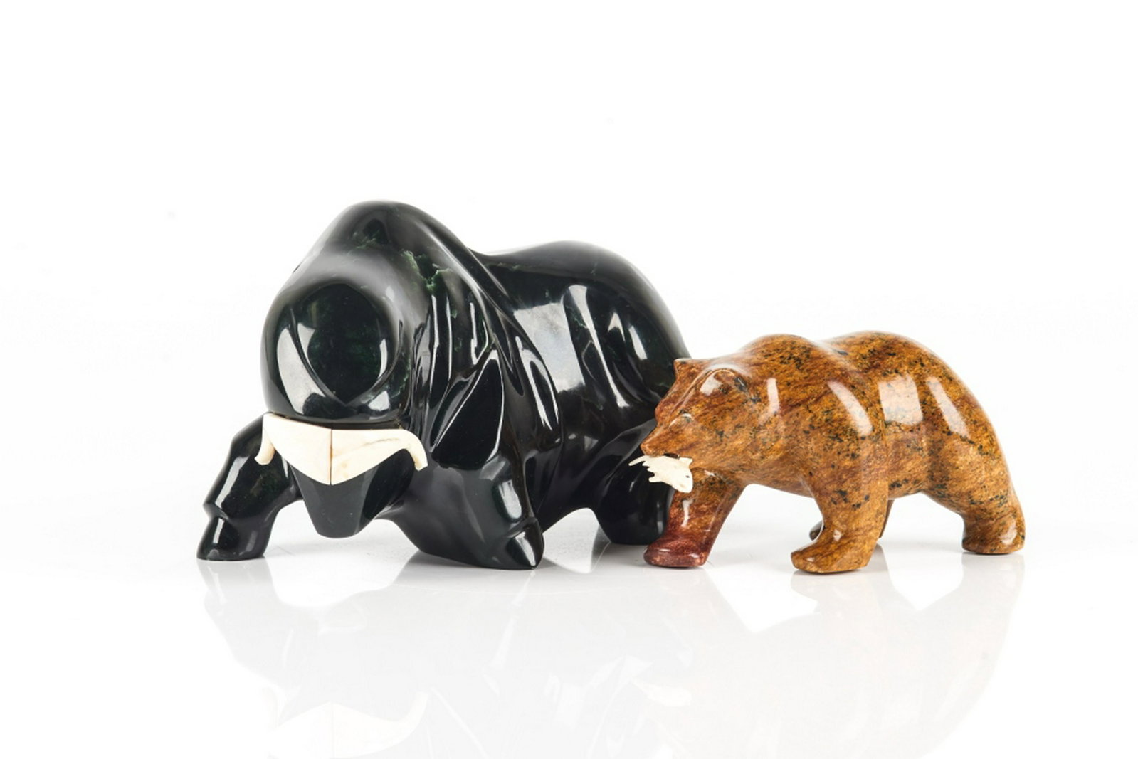 LYLE SOPEL (Canadian, b. 1951): A carved nephrite arctic muskox signed "Sopel 370 4/80" to the base. Together with a carved soapstone polar bear with a fish caught in its mouth, signed Hook to foot. L. of muskox: 20.3 cm (8 in.)