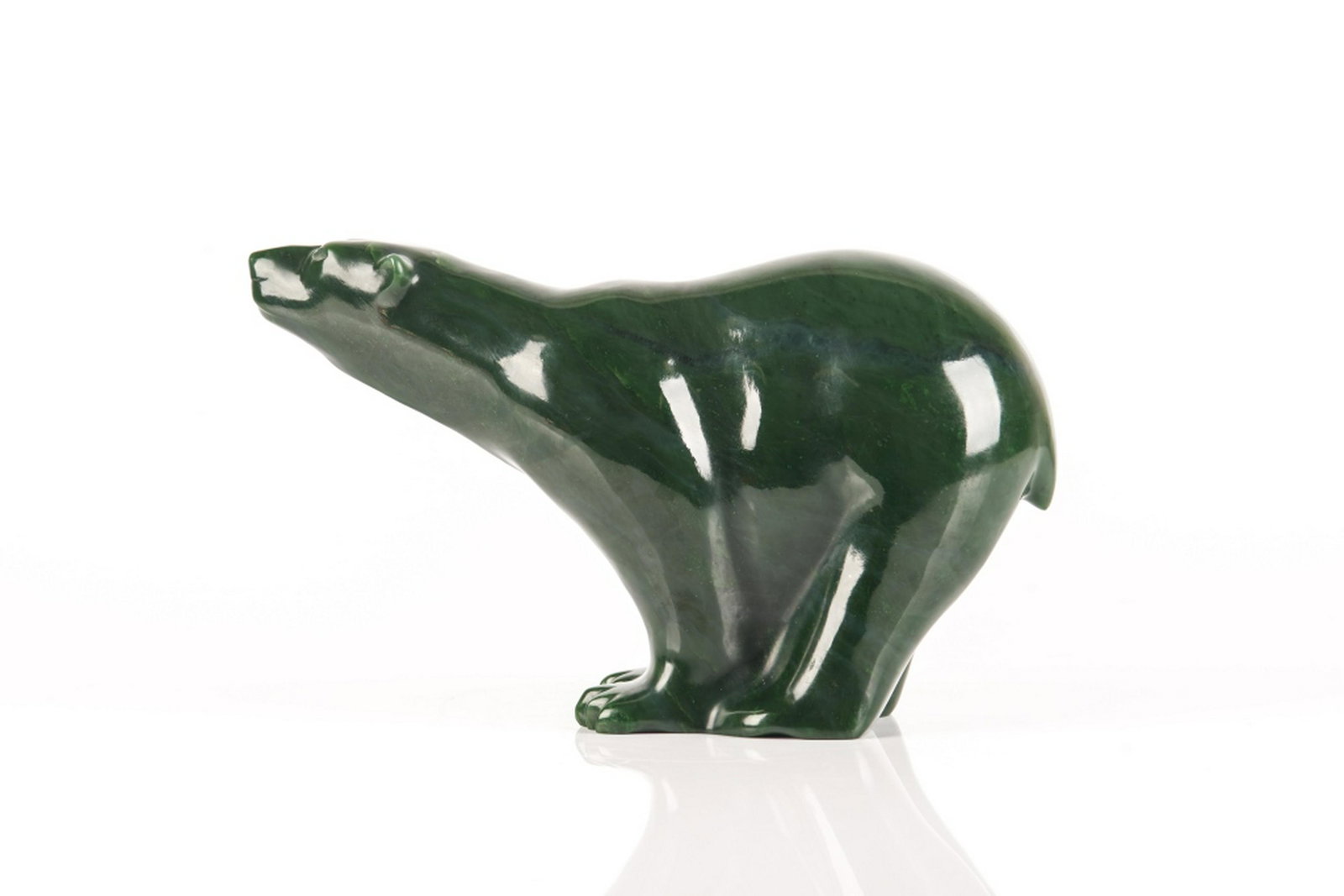 CARVED GREEN NEPHRITE BEAR, "NANOOK": A carved spinach coloured Canadian jade of the polar bear, Nanook, in the manner of Lyle Sopel. Signed to base "NANOOK 1068" and "John Charles Lundgren. L. 33 cm (13 in.)