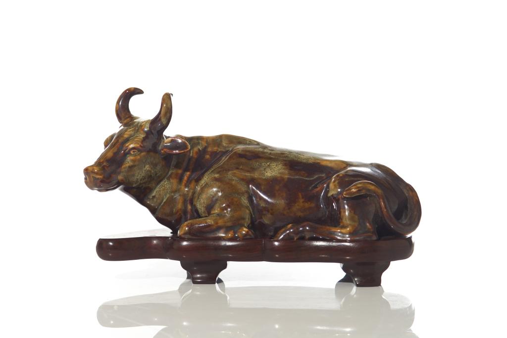MOTTLED GLAZED POTTERY WATER BUFFALO: 晚清 瓷塑牛（带座） Reclining, with fitted hardwood stand. Qing dynasty, 19th C. L. 26cm (10 in.)