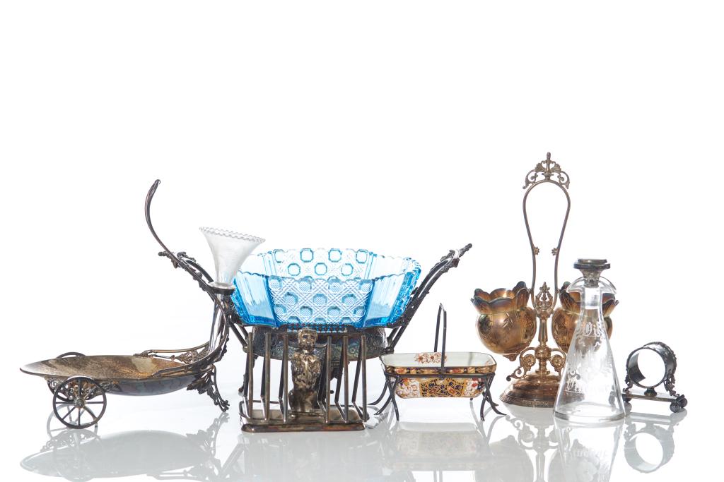 ASSORTED LOT OF DECORATIVE TABLE ACCESSORIES: Seven pieces in total. Including a blue glass bride basket centerpiece with silverplate stand, a silverplate figural dog napkin holder, napkin ring with base, a unique wagon shaped centerpiece with a