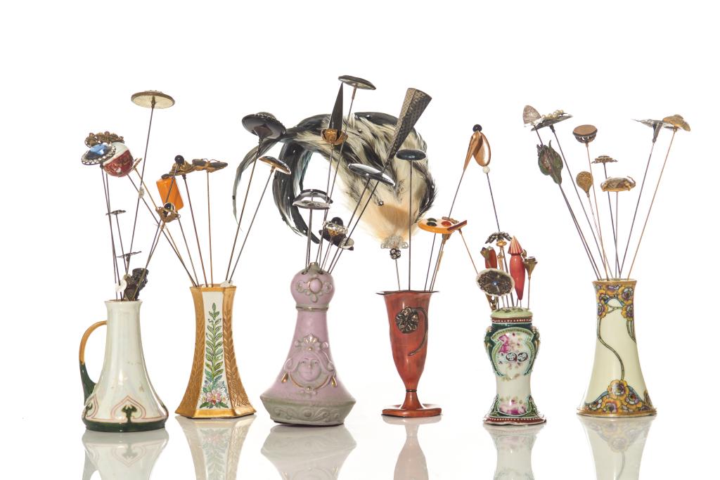 ASSORTED LOT OF HAT PINS WITH STANDS: Six hat pin stands in various shapes and patterns, including two porcelain stamped by Nippon and Limoges respectively. Stands include an assortment of 50 vintage hat pins. H. of tallest stand 15 cm (5