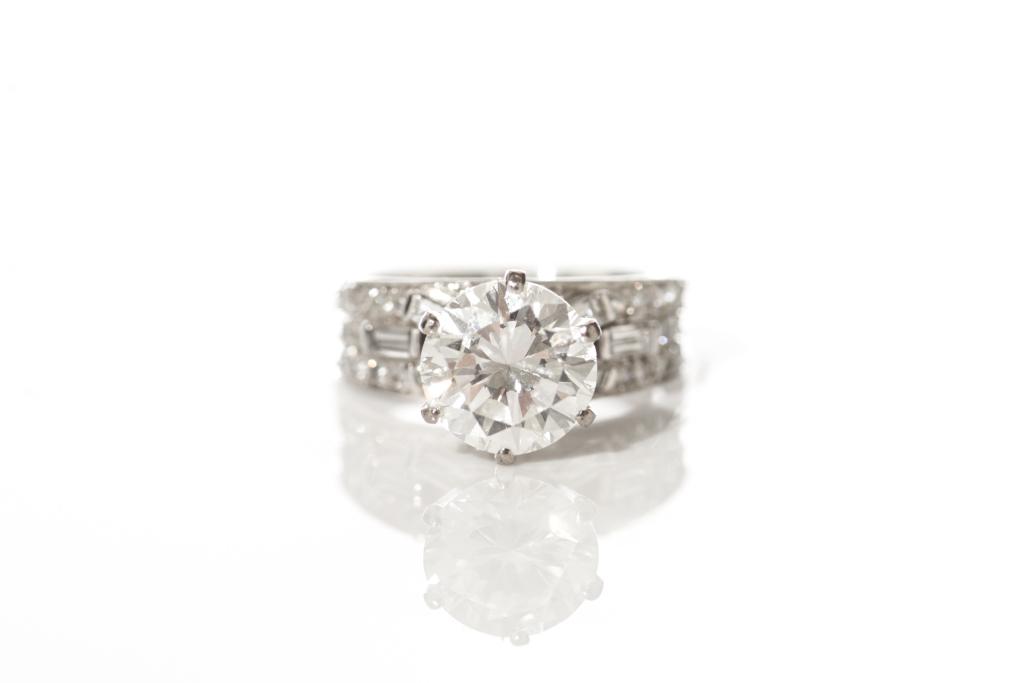 GOLD & DIAMOND SOLITAIRE RING: White gold band stamped 14k and set with a central brilliant cut diamond 2.25 ct., the band triple stacked with six channel set pave and baguette diamonds. Total weight of diamonds 2.80 ct., total wei
