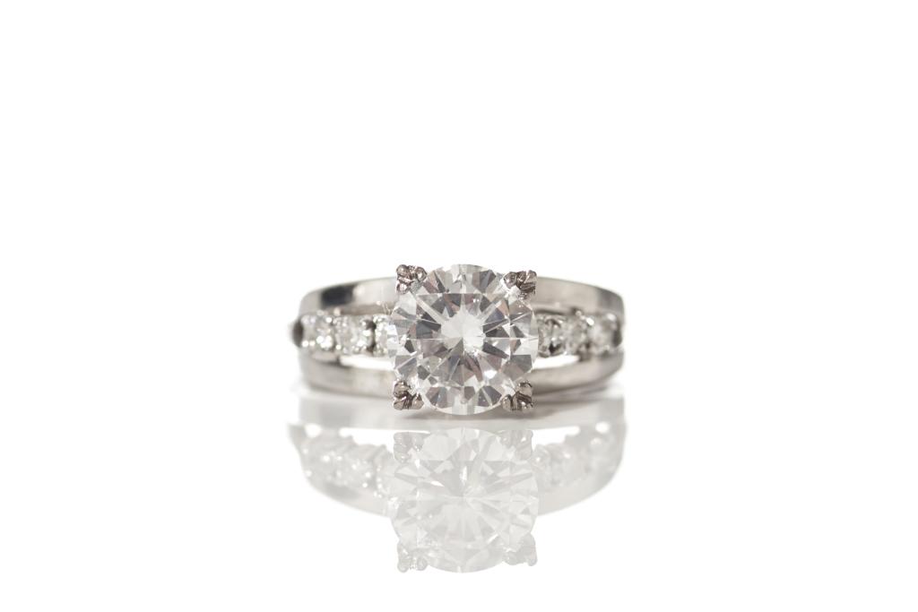 GOLD & DIAMOND SOLITAIRE RING: 14k white gold band stamped HR and .585, set with a central round brilliant cut diamond 1.35 ct and flanked by three smaller diamonds on each side. Total weight of diamonds1.53 ct, total weight of rin