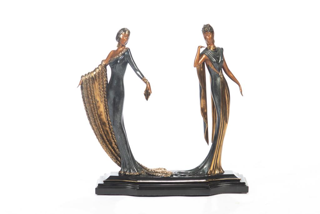 After ERTE (Russian/ French, 1892-1990): A patinated bronze of two women in the Art Deco style. Figures are posed in long glamorous gowns, with light brown patina for their skin and gilded detailing to their dresses. Mounted on a black base,