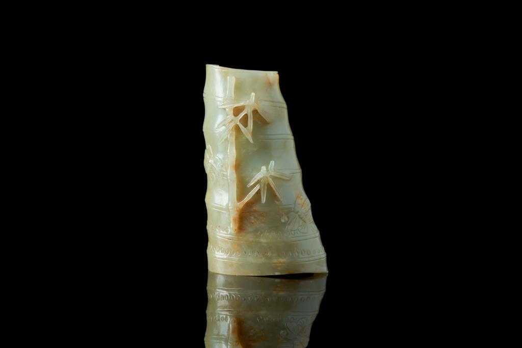 CHINESE CELADON JADE CARVED WRIST REST: Jade in celadon tone with russet and white inclusions. Carved as a bamboo shoot form wrist rest with further relief carving of bamboo and butterflies on the front, and insects on the underside. Qing d