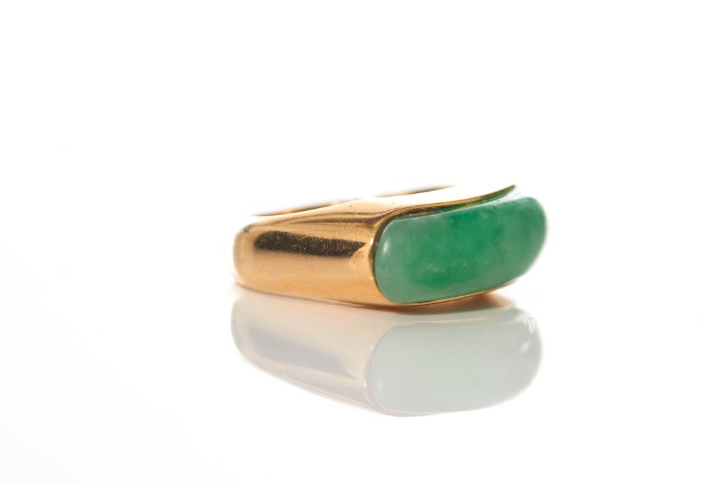 CHINESE JADEITE SADDLE RING IN YELLOW GOLD: Pale green rectangular jadeite cabochon with apple green and white occlusions set in a yellow gold saddle-style ring. Cabochon appears untreated and no signs of fluorescing under UV light. Size 6.5. C