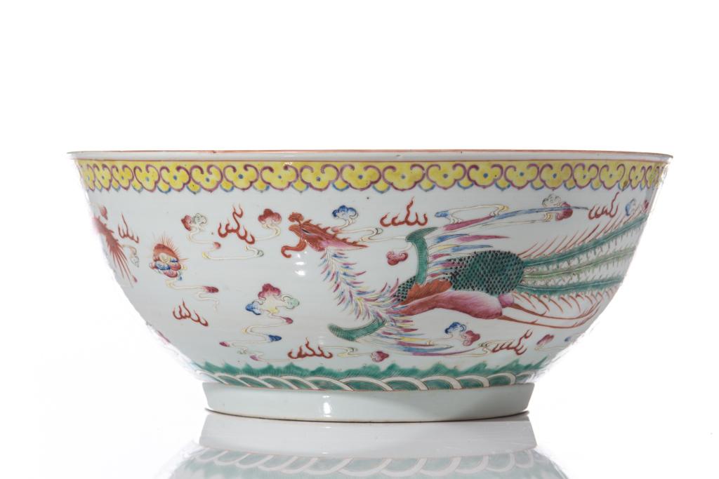 LARGE FAMILLE ROSE PORCELAIN DRAGON PUNCH BOWL: Painted on the exterior with an iron red dragon and famille rose phoenix amongst clouds, in between a band of yellow ruyi to top and green waves to foot. Interior with a dragon roundel. Six character