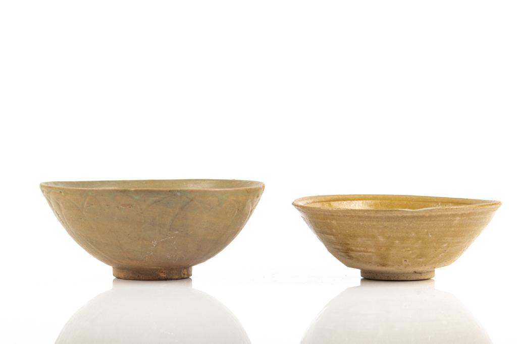 TWO EARLY CHINESE CELADON GLAZED POTTERY BOWLS: The larger bowl of a Longquan celadon type with lotus patterns on the exterior. The smaller bowl glazed in olive green crackled glaze. Ming dynasty or earlier. Larger dia. 19cm (7 1/2 in.)