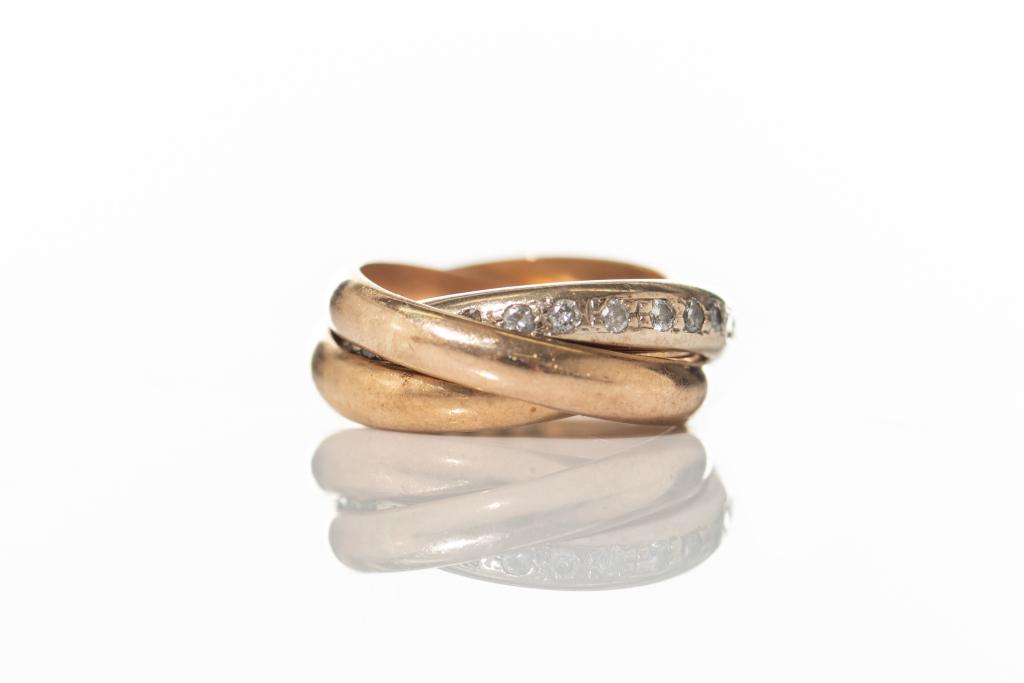 CARTIER-STYLE TRINITY RING WITH DIAMONDS: 18k yellow, rose and white gold rolling ring, comprised of three interlaced bands. White gold band set with twenty-eight small round brilliant cut diamonds, weighing approx. .50cts in total by gauge. 