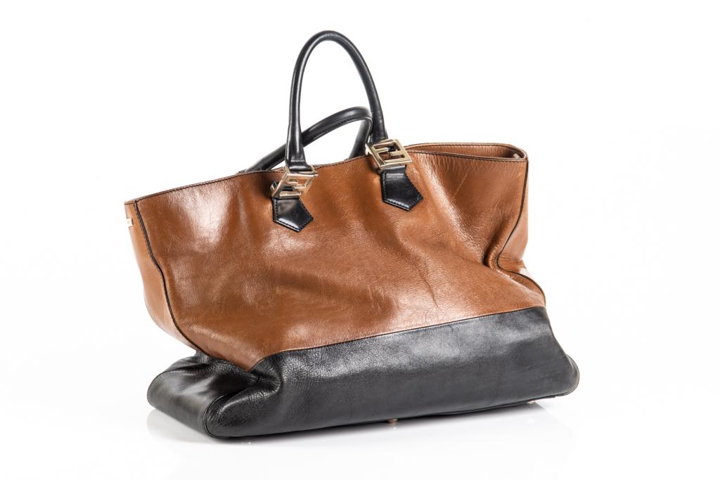 FENDI BROWN AND BLACK LEATHER HANDBAG: Two-tone leather handbag with two top handles. Handles are accented with iconic gold Fendi hardware. Open bag with a metal snap closure and side zippered pocket on the interior. L. 16in. H. to top of 