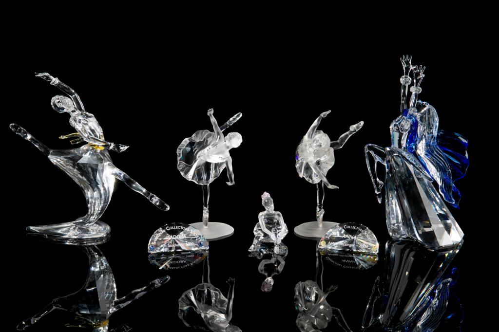 SWAROVSKI CRYSTAL COLLECTION OF DANCERS: Group of five figurines, including: a pair of bejeweled and frosted dancers, a young girl putting on her shoes wearing a pink bow, and two "Magic of Dance" figurines "Anna" and "Isadora"(both with acc
