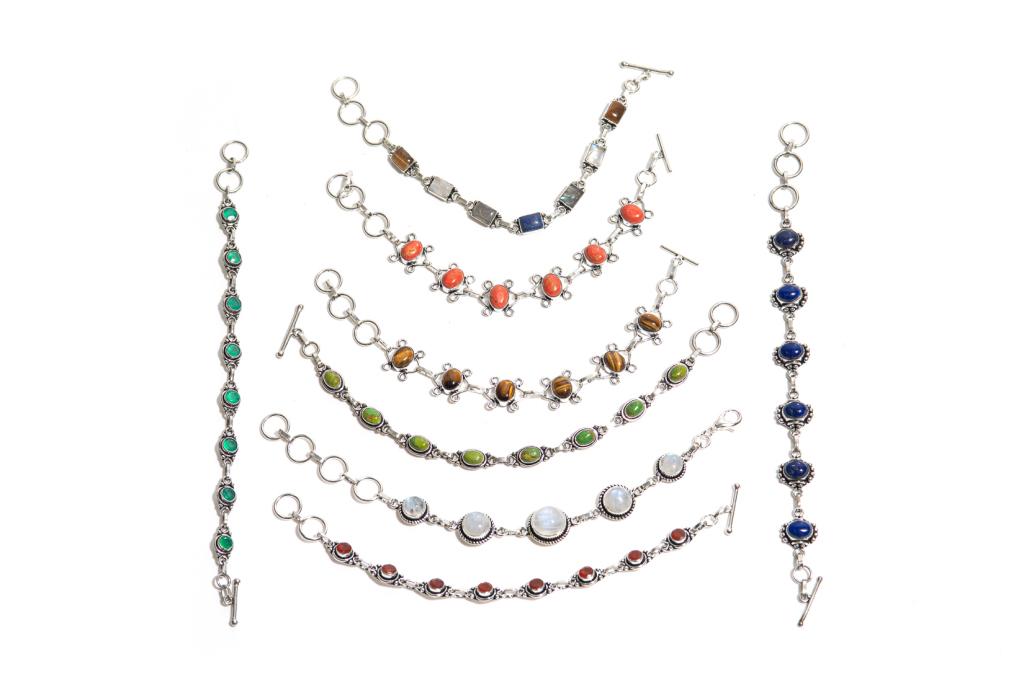 EIGHT SILVER BRACELETS: Eight silver link bracelets with toggle closures, embellished with various bezel set coloured stones. Length: 7 1/2 in.