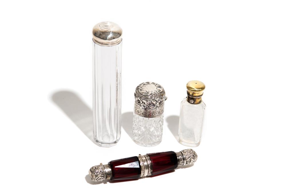 FOUR GLASS AND SILVER TOILETTE BOTTLES: A silver mounted double ended bottle that opens in the middle. Together with three other silver mounted glass toilette bottles. Tallest of the bottles bears hallmarks for Dimier Brothers & Co.London, 