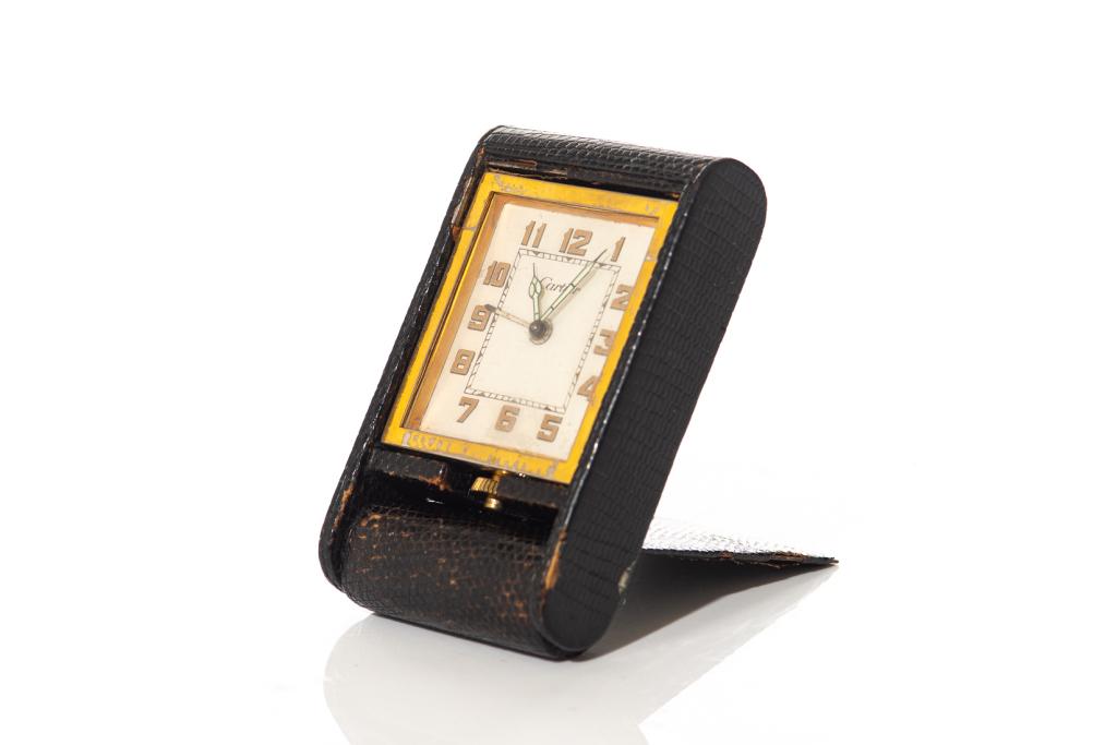 VINTAGE CARTIER MECHANICAL TRAVEL DESK CLOCK: In a folding compact black leather case. Winding mechanism to the bottom of clock. H. of clock 6 cm (2 3/8 in) H. including case 10.5 cm (4 1/8 in)
