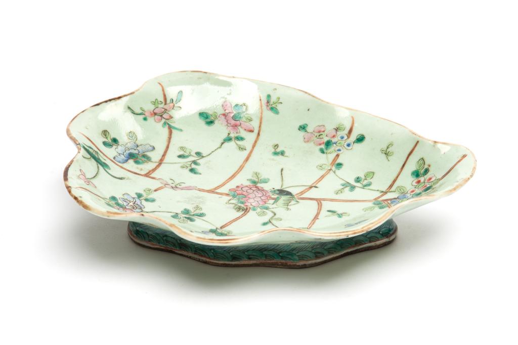 CELADON GLAZED FAMILLE ROSE PORCELAIN LEAF DISH: Painted with flowers and butterflies with gilt veins. Four character Tongzhi mark to base and of the period. L. 29cm (11 1/2 in.) Condition report available upon request.